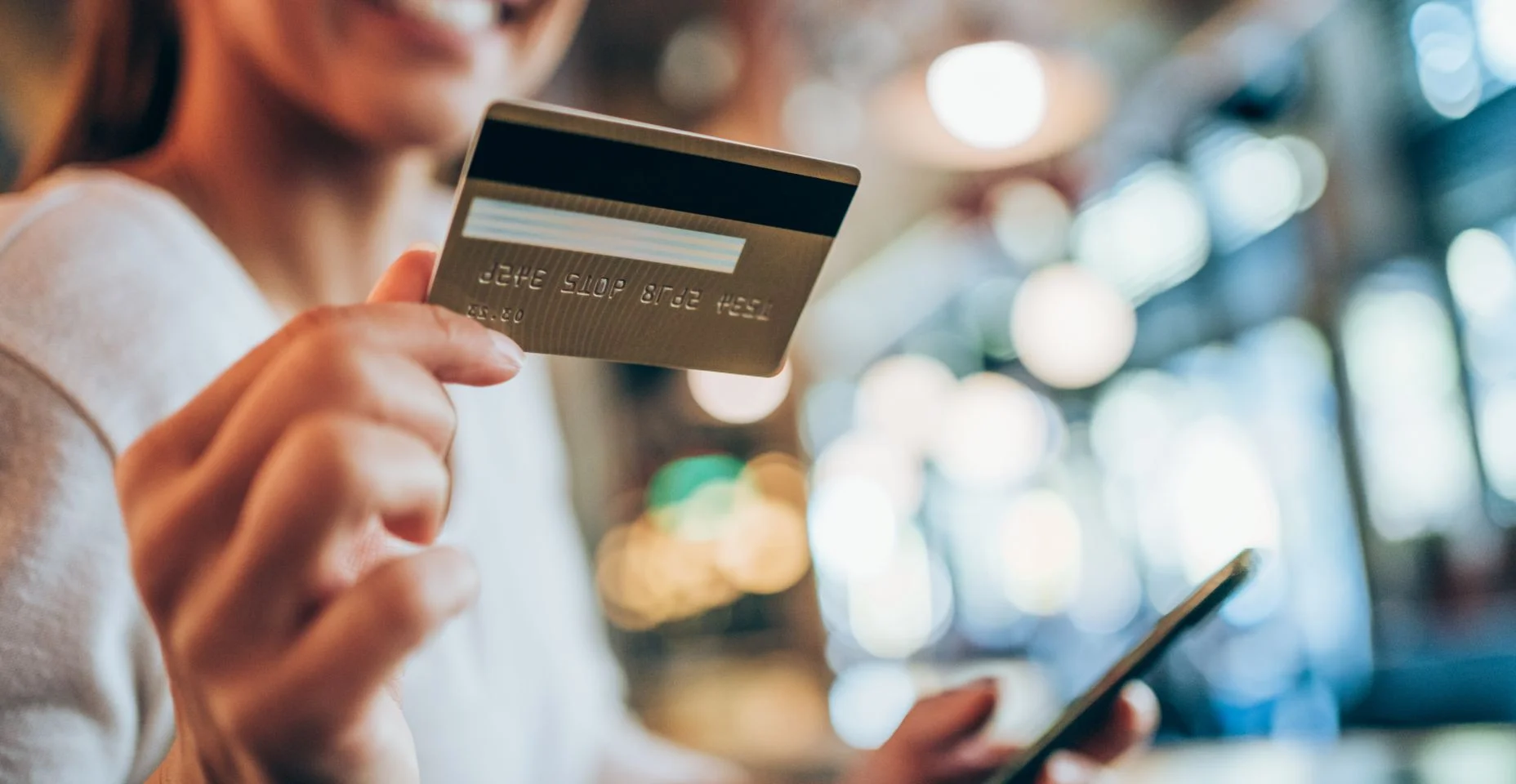 Mulher usando telefone inteligente e cartão de crédito para compras online no City Café.