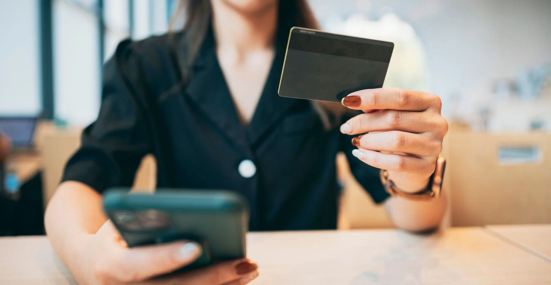 Um empresário está usando um cartão de crédito para fazer uma compra online em um café.