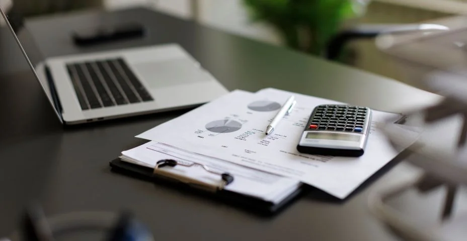 calculadora, papelada e notebook