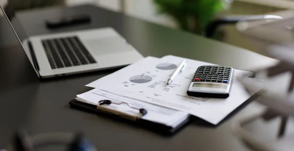 calculadora, papelada e notebook