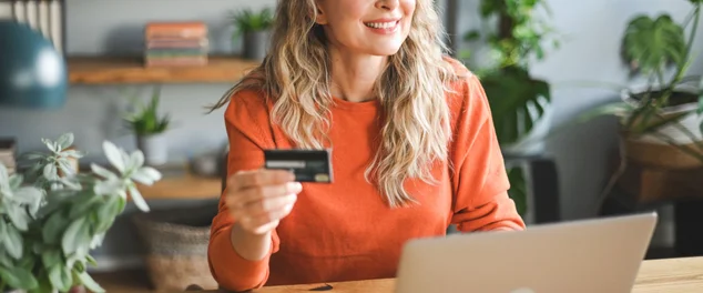 Mulher adulta madura que trabalha em casa (laptop, cartão de crédito)