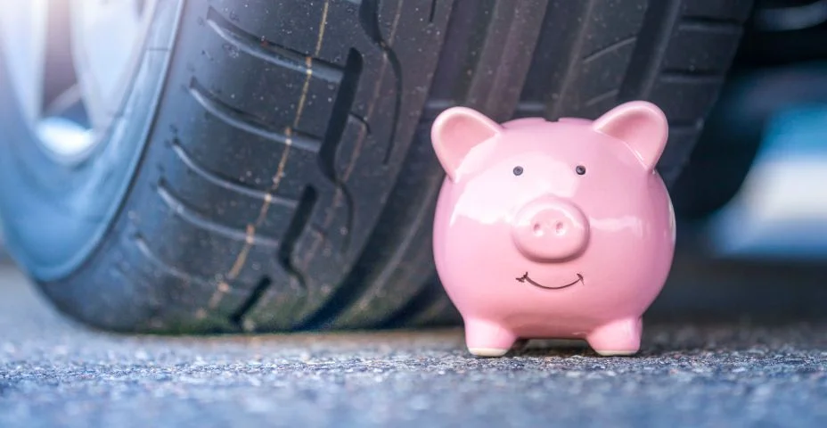 Cofrinho rosa senta-se ao lado do novo pneu de um carro moderno