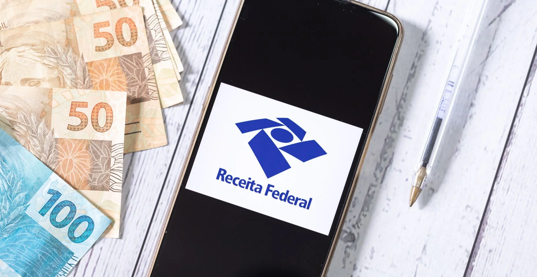 Um telefone celular com a logo da Receita Federal do Brasil e uma calculadora na composição da imagem. Imposto de renda, darf, declaração anual, restituição do imposto de renda.