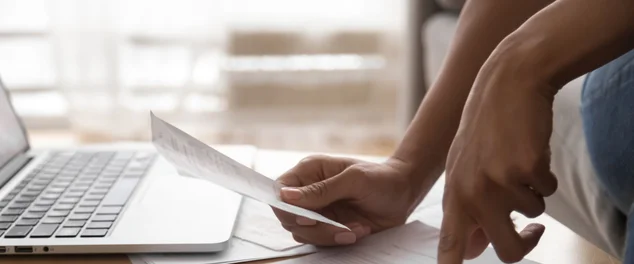 Homem com uma conta e seu notebook vendo os passos para limpar o nome