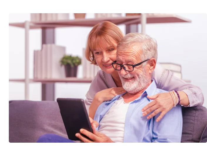 Retrato de casal de idosos alegres na sala de estar, idosa e um homem usando smartphone falando em vídeo chamada em sofá aconchegante em casa, conceitos de família feliz