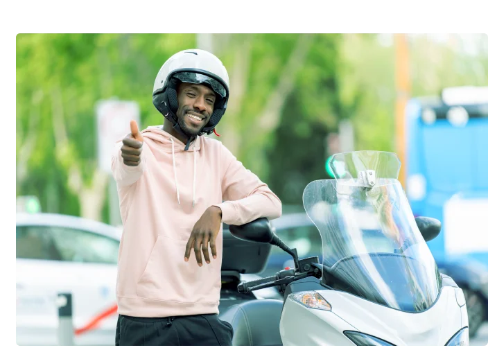 homem do lado de uma moto fazendo um joinha.