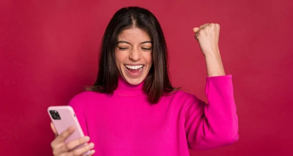 Mulher animada com smartphone celebrando a vitória