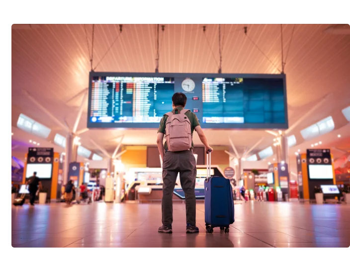 homem no aeroporto com mala olhando para telão