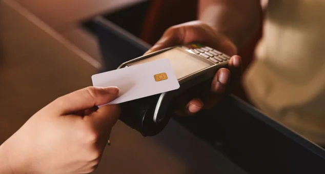 Fechar assistente de vendas em loja de varejo com cliente pagando usando cartão de crédito contactless cartão de crédito NFC