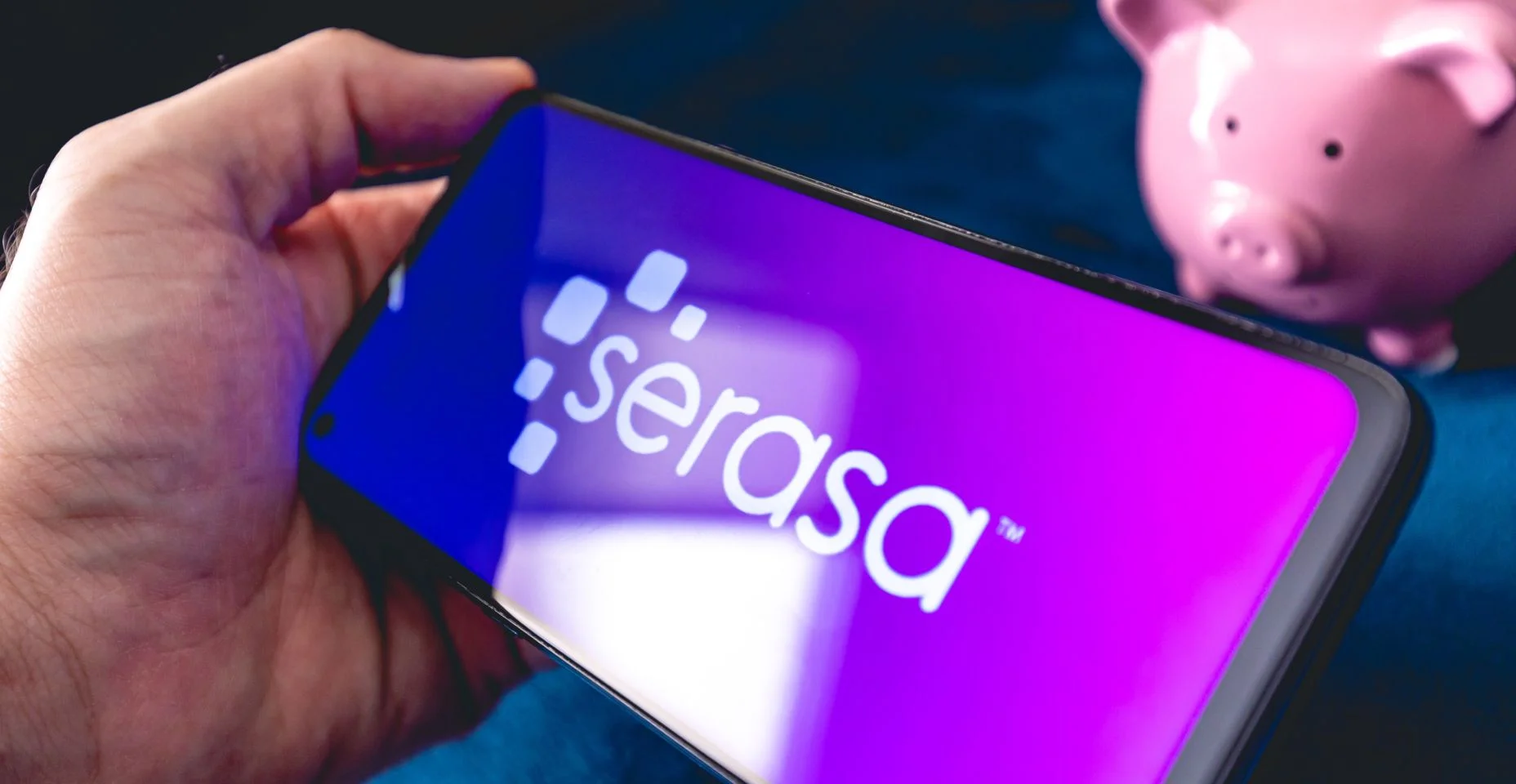 Um homem segurando um telefone celular com a logo da empresa brasileira Serasa.