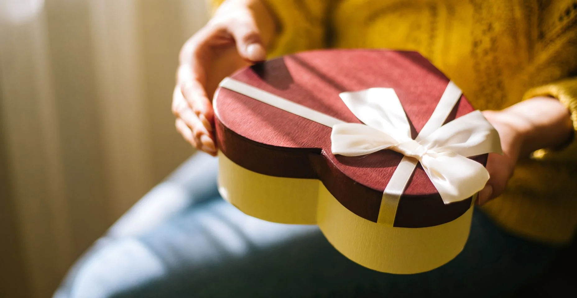 Mulher nova que prende a caixa de presente do dia do Valentim