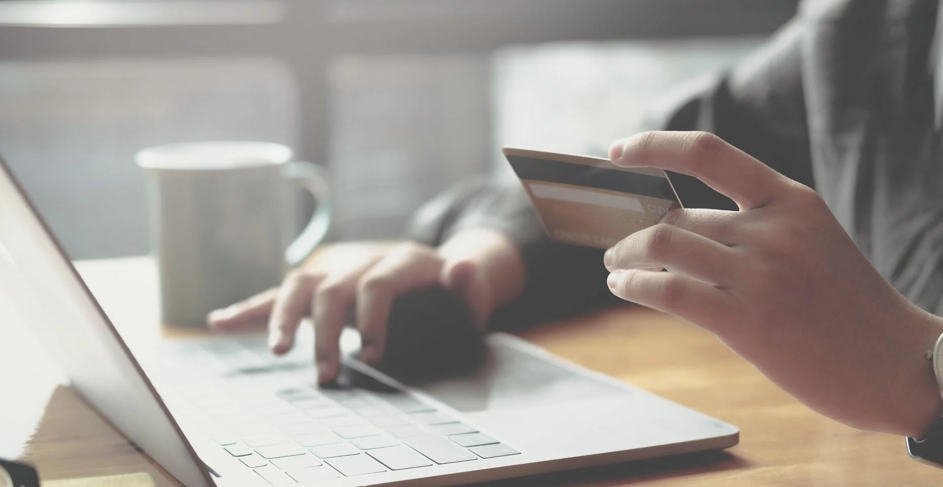 Pagamento online, mãos da mulher segurando um cartão de crédito e usando laptop para compras online.