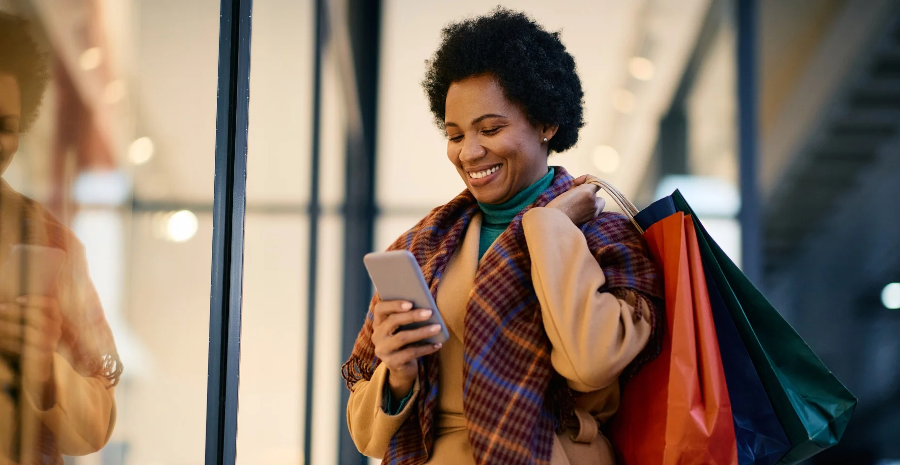 Mulher negra feliz mandando sms no celular enquanto fazia compras na cidade.