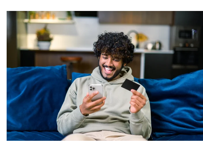 homem com cartão e celular na mão com uma cara de Feliz