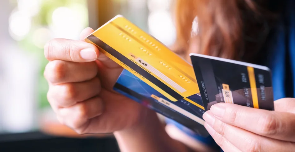 Imagem aproximada de uma mulher segurando e escolhendo um cartão de crédito para usar