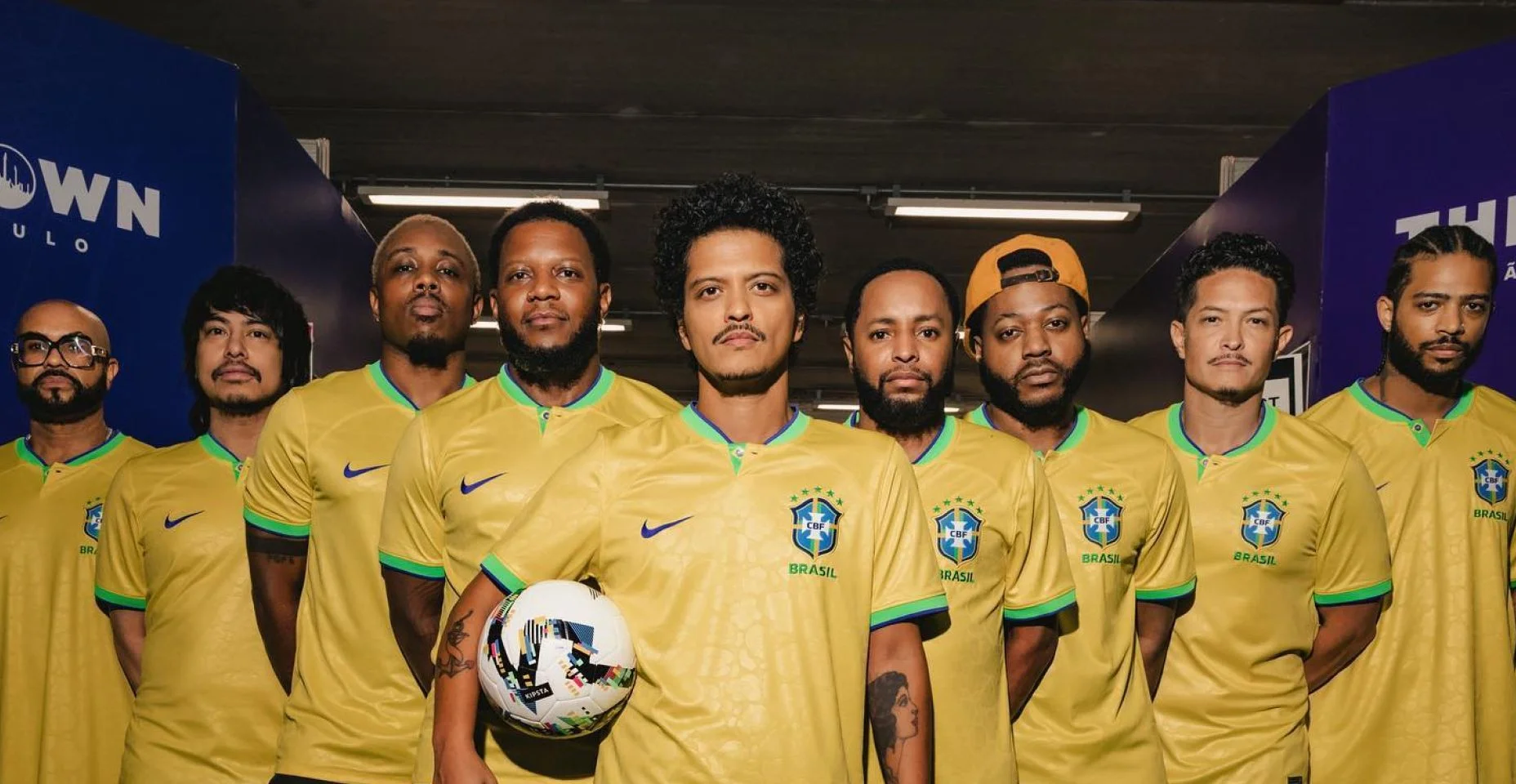 Bruno Mars e banda vestidos com a camiseta do time de futebol nacional do Brasil