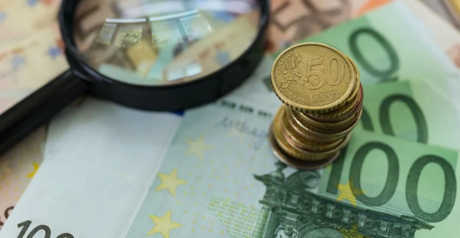 Pilha de Euro moedas na pilha de notas com lupa como conceito de negócio financeiro imposto