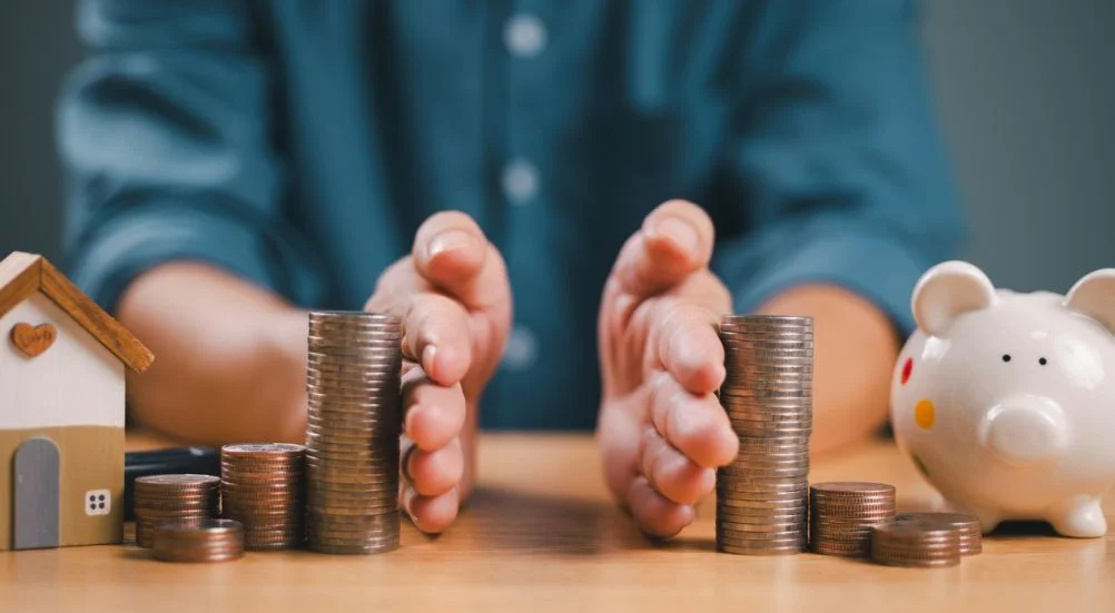 Mão separada economizando dinheiro, finanças, empréstimo à habitação, retorno da dívida com cofrinho e casa de madeira. Investimento em negócios bancários