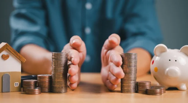 Mão separada economizando dinheiro, finanças, empréstimo à habitação, retorno da dívida com cofrinho e casa de madeira. Investimento em negócios bancários