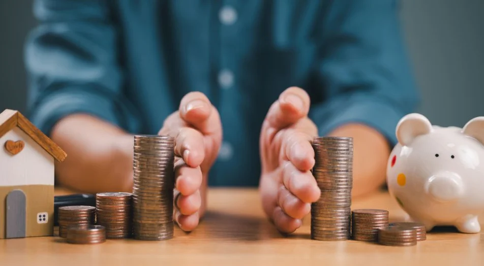 Mão separada economizando dinheiro, finanças, empréstimo à habitação, retorno da dívida com cofrinho e casa de madeira. Investimento em negócios bancários