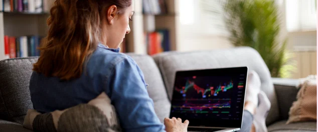 mulher mexendo no computador verificando gráficos da bolsa de valores