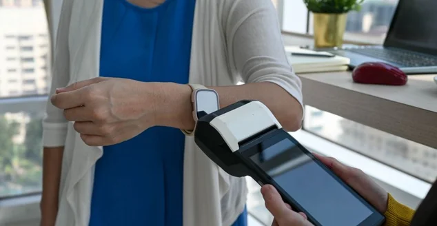 Mulher usando terminal POS para pagamento sem contato via smartwatch em um café. Nova tecnologia de pagamento NFC -