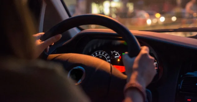 Mulher solteira dirige carro segurando o volante viajante de gás baixo