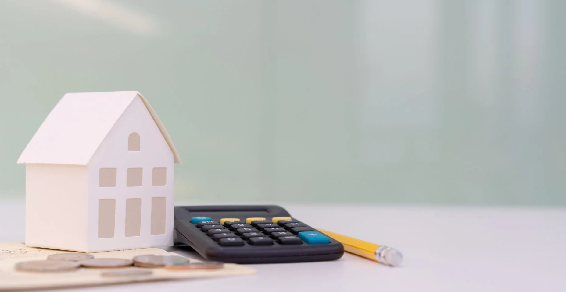 Fechar o modelo da casa sobre livro de contas bancárias com calculadora, moeda e lápis na mesa para o planejamento de refinanciamento de hipotecas de crédito imobiliário ou taxas de juros de retenção, negócios e conceito financeiro