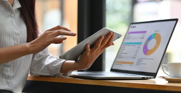 Close up de Empresária analisando tabelas e gráficos de renda com notebook e tablet modernos. Análise de negócios e conceito de estratégia