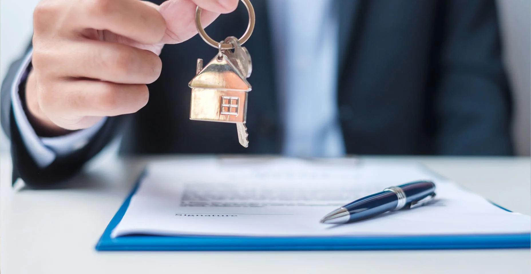 Homem segurando chave de casa durante a assinatura de documentos de contrato de casa.