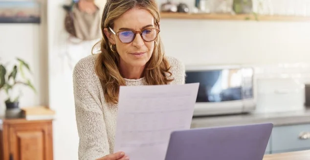 Mulher de orçamento, finanças e aposentadoria com laptop e papelada para poupança de pensão, contas ou investimento de renda no aplicativo de banco digital. Pessoa idosa com hipoteca, documento financeiro ou gestão fiscal