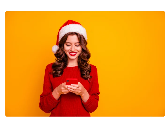 mulher mexendo no celular com touca de natal
