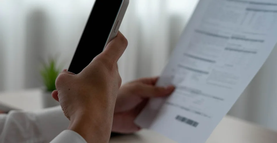 Um empresário usa seu telefone para escanear um código de barras para pagar sua fatura mensal do cartão de crédito depois de receber uma fatura. conceito de pagamento de faturas online