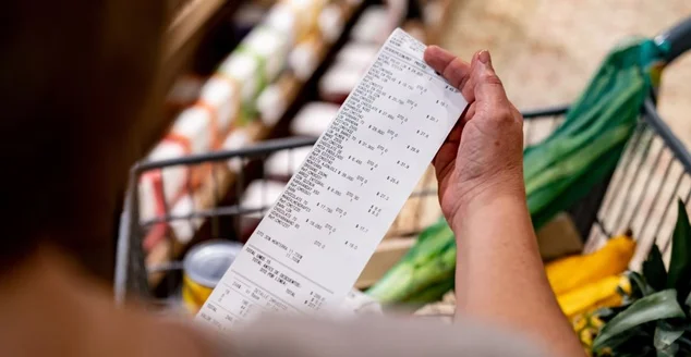 Mulher olhando para um recibo depois de fazer compras no supermercado