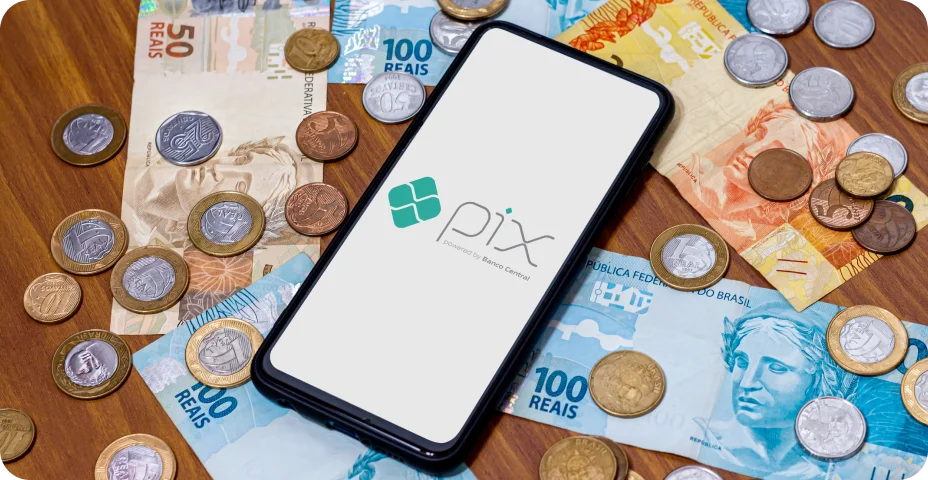 Logotipo do Pix na tela do smartphone com várias moedas ao redor. O Pix é o novo sistema de pagamento e transferência do governo brasileiro.