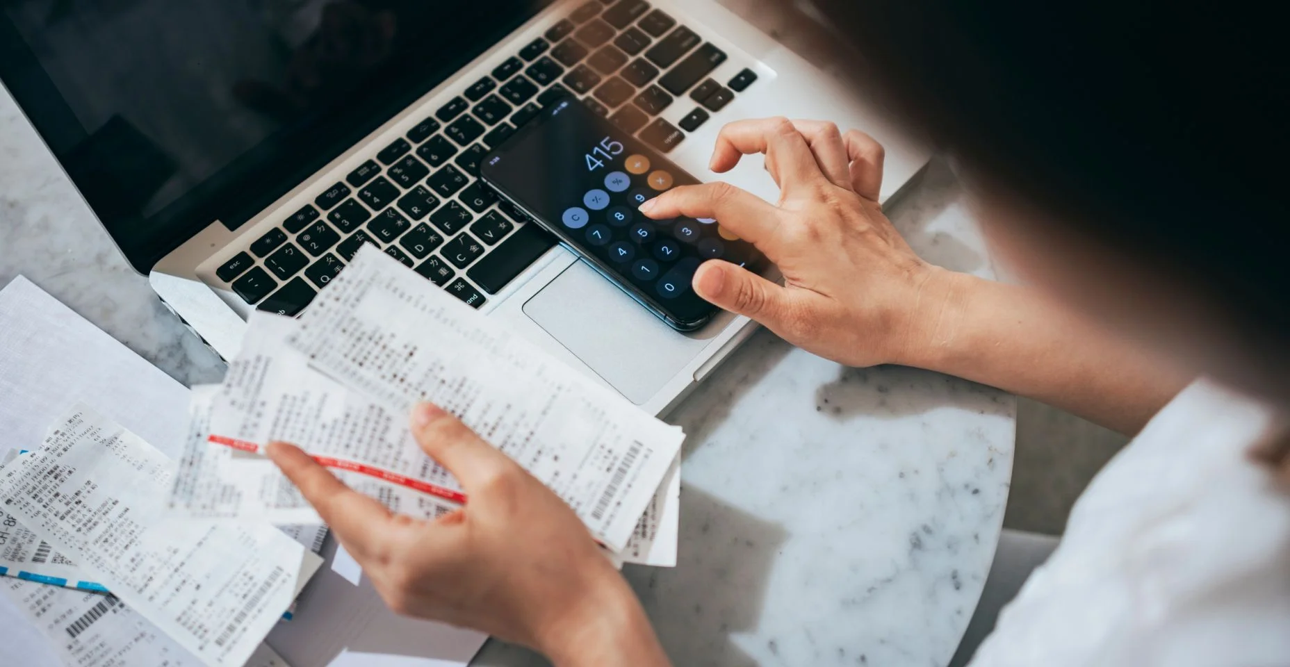 Visão aérea de uma jovem asiática gerenciando serviços bancários pessoais e finanças em casa. Planejando orçamento e calculando despesas enquanto verifica suas contas com a calculadora.