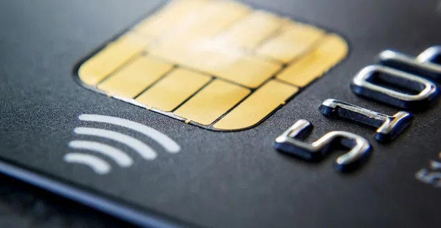 Close-up of black plastic credit card with chip and contactless pay technology. Macro photography of a bank credit card on a table.