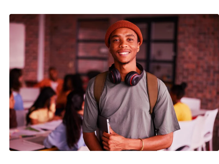 Sorrindo jovem estudante universitário usando fones de ouvido em pé em uma sala de aula