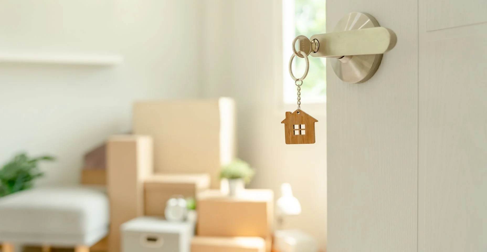 Mudança de casa, realocação. A chave foi inserida na porta da nova casa, dentro do quarto havia uma caixa de papelão contendo pertences pessoais e móveis. mudança no apartamento ou condomínio