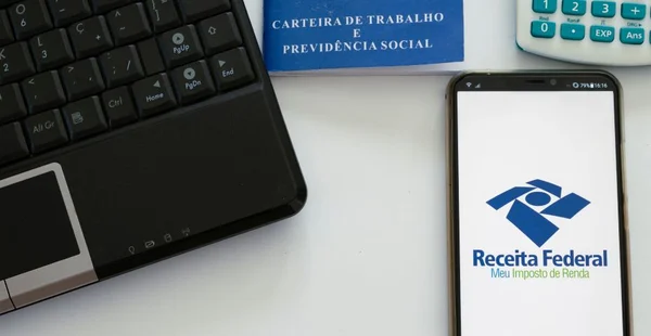 celular com aplicativo de declaração de imposto de renda, computador, calculadora e carteira de trabalho brasileira. Conceito de pagamento de impostos imposto de renda brasil