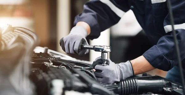 Mecânico trabalha no motor do carro na garagem. Serviço de reparo. Conceito de serviço de inspeção de carros e serviço de reparo de carros.