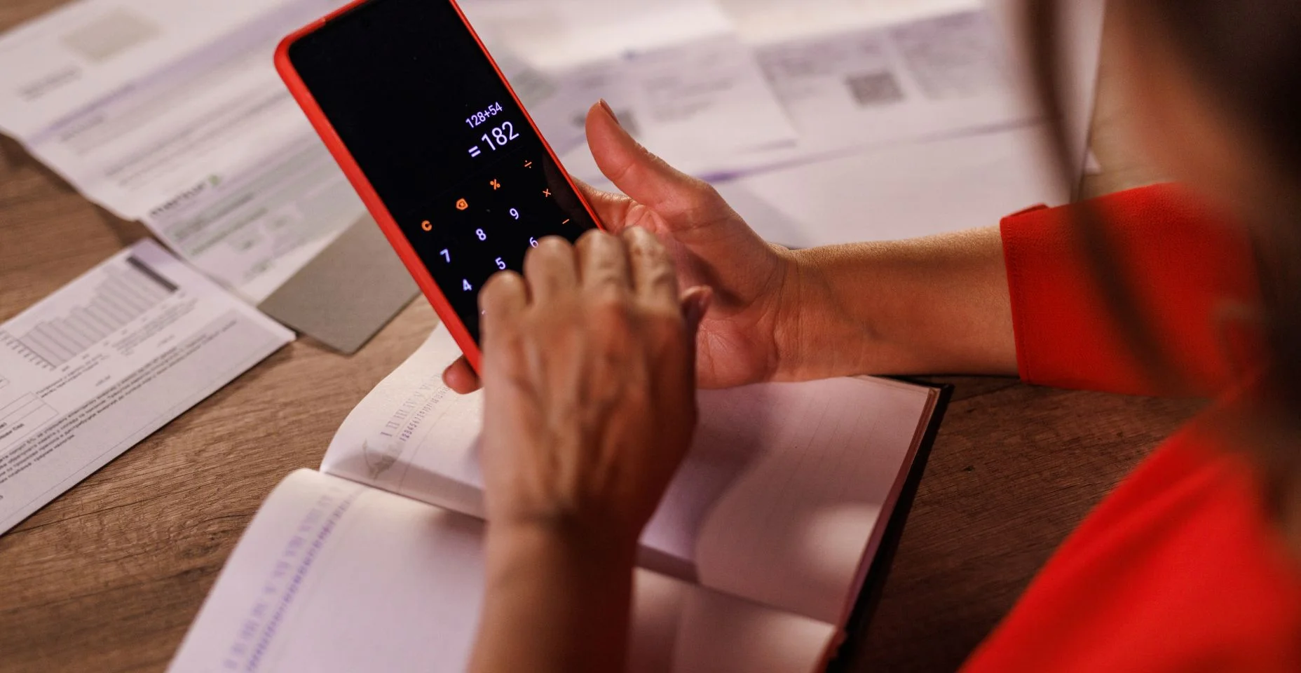 Mulher usando uma calculadora ao fazer as finanças na mesa do escritório em casa durante as férias de Natal