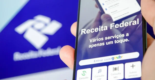 Imposto de renda 2024 da receita federal segurando celular com aplicativo e dinheiro