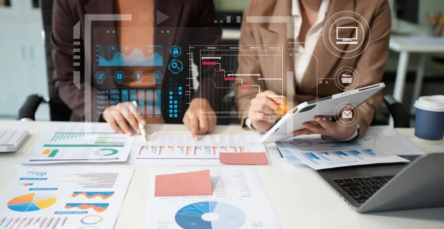 Equipe de empresários ou analistas de dados financeiros trabalhando juntos com tablets, laptops e gráficos de dados. Planejam analisar projetos no escritório.