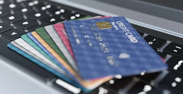 Pilha de cartão de crédito colorido em um laptop prateado. Ilustração do conceito de consumismo de cartão de crédito