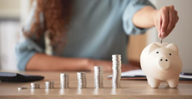 Jovens afro-americanas dinheiro colocando moedas em um cofrinho em casa. Pessoa mestiça contando moedas enquanto planejamento financeiro em sua sala de estar. Economizando, investindo e pensando no futuro