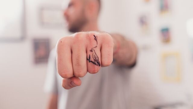 homem com tatuagem no dedo anelar