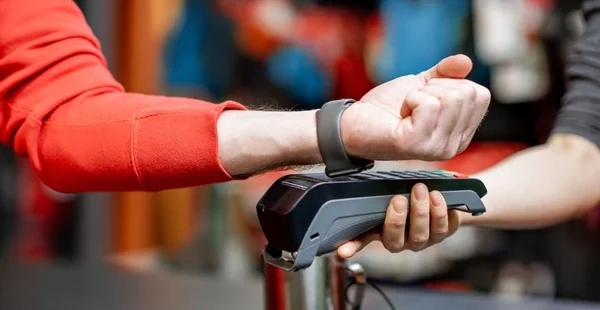 Homem usando relógio manual na caixa registradora para comprar mercadorias na loja de esportes, close-up sem rosto