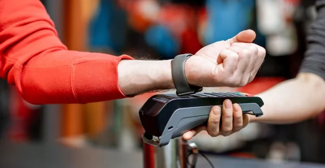 Homem usando relógio manual na caixa registradora para comprar mercadorias na loja de esportes, close-up sem rosto