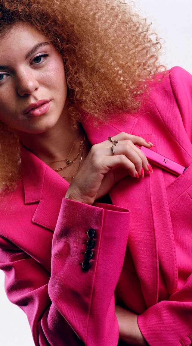 Woman in pink putting a pink Pax Era in her breast pocket